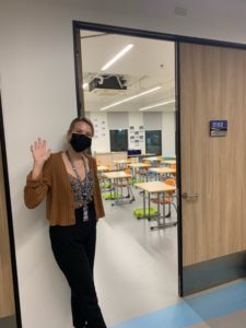 Teacher waving outside classroom